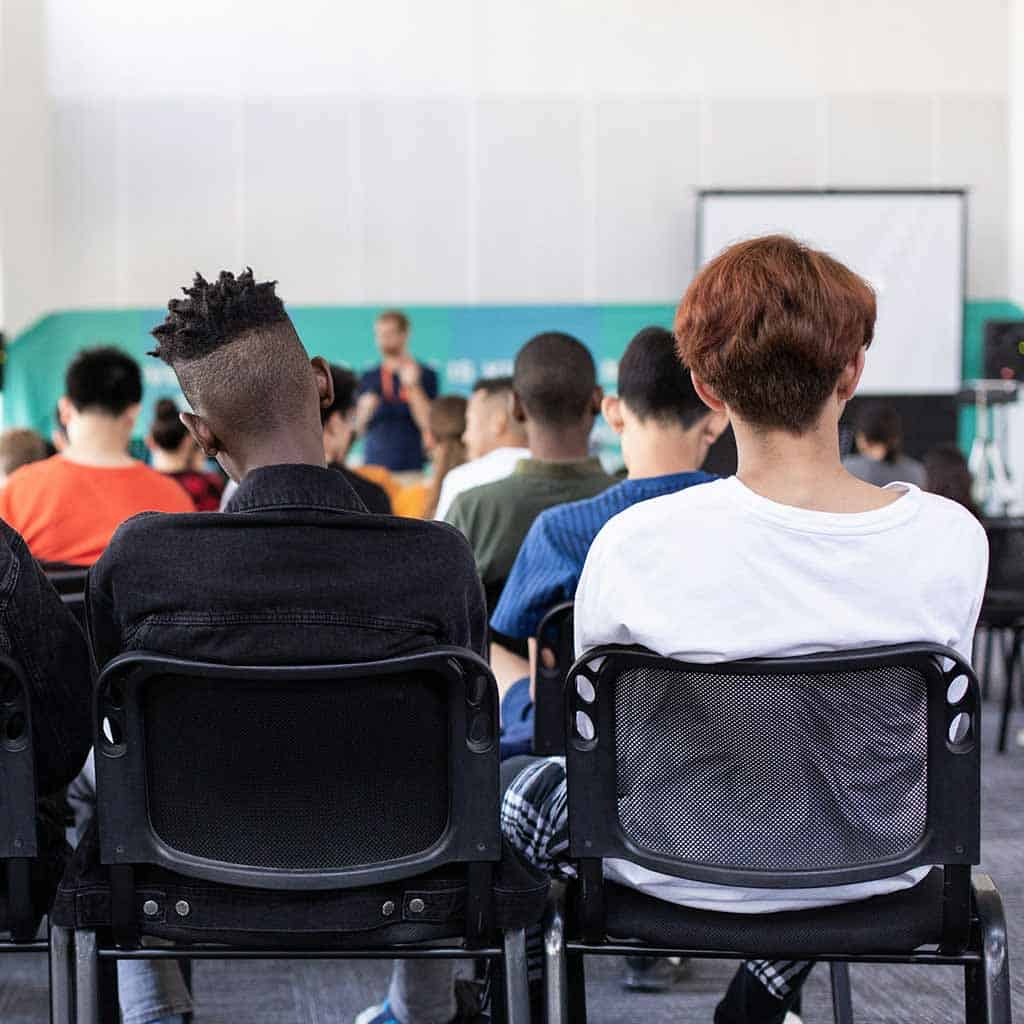 Students sitting in a classroom listening to their teacher.